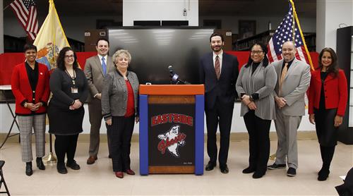 Several people pose while standing on either side of a podium.